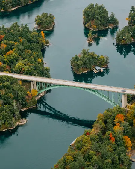 Gananoque y Mil Islas Puente de las Mil Islas que conecta Ontario y el estado de Nueva York, abarcando islas boscosas con follaje otoñal y aguas tranquilas debajo.