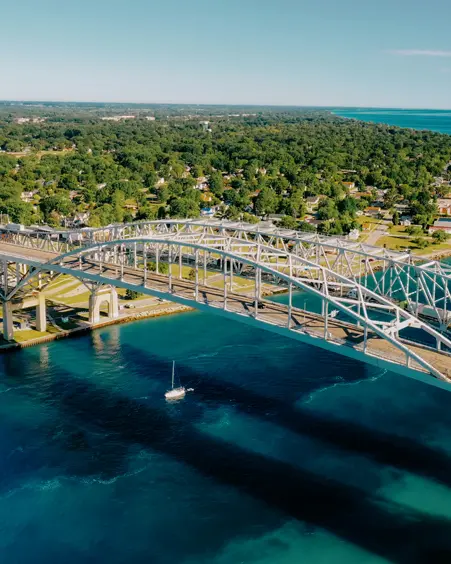  Vista aérea del puente Blue Water que cruza el brillante río azul St. Clair, conectando Sarnia y Port Huron, con una exuberante costa verde.