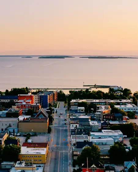 Vista aérea del centro de North Bay al anochecer, con la costa brillante y las islas Manitou visibles en la distancia.