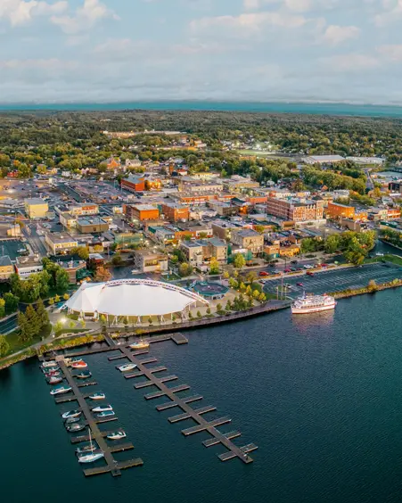 Aerial view of Kenora, Ontario at sunset, with boats docked along the shoreline and soft purple clouds over Lake of the Woods.