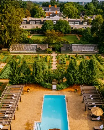  Luftaufnahme von Langdon Hall in Cambridge, Ontario, mit einem formellen Garten, einem Außenpool und einem historischen Landsitz, umgeben von Wald.