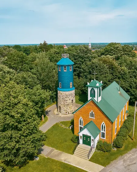 Luftaufnahme des Higginson Towers und der St. John the Apostle Anglikanischen Kirche in Vankleek Hill, umgeben von grünen Bäumen an einem Sommertag.
