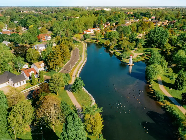 Vue aérienne du parc Wellington, à Simcoe, montrant une rivière sinueuse, des arbres verts et une structure de style de phare dans l’eau.