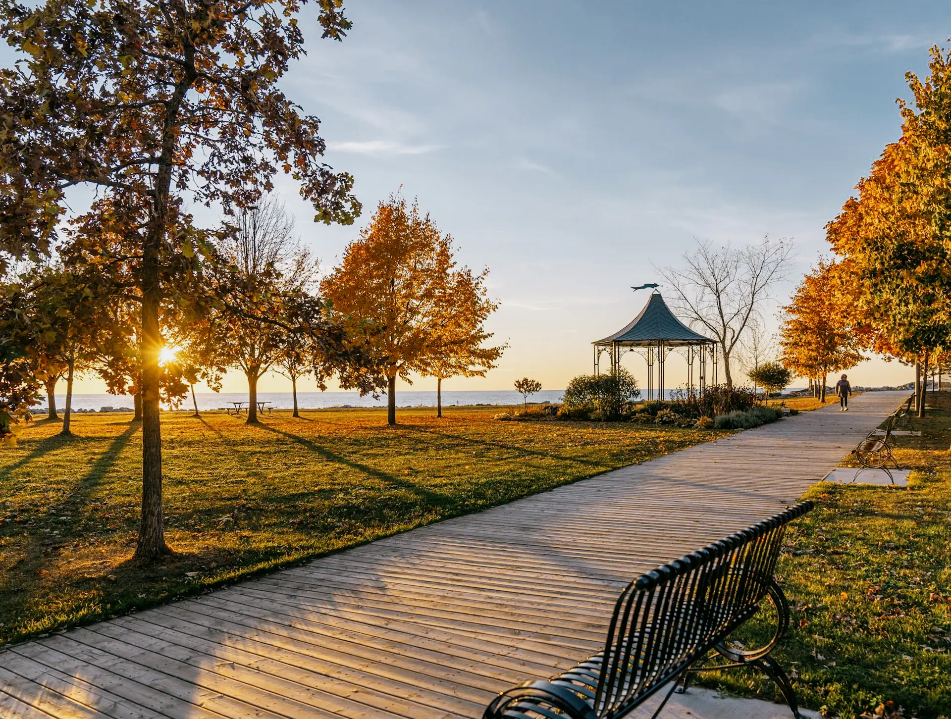 나무와 검은색 벤치가 늘어선 산책로를 따라가면 고더리치 해안가의 일몰 무렵 정자로 이어진다.