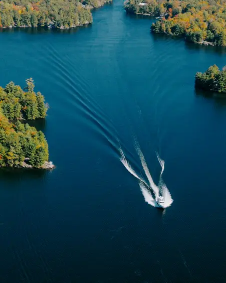 Orillia et la Région des Lacs Deux bateaux naviguant sur un lac bleu en laissant des traces blanches, entourés d’une rive boisée, à Orillia, dans la région des lacs.