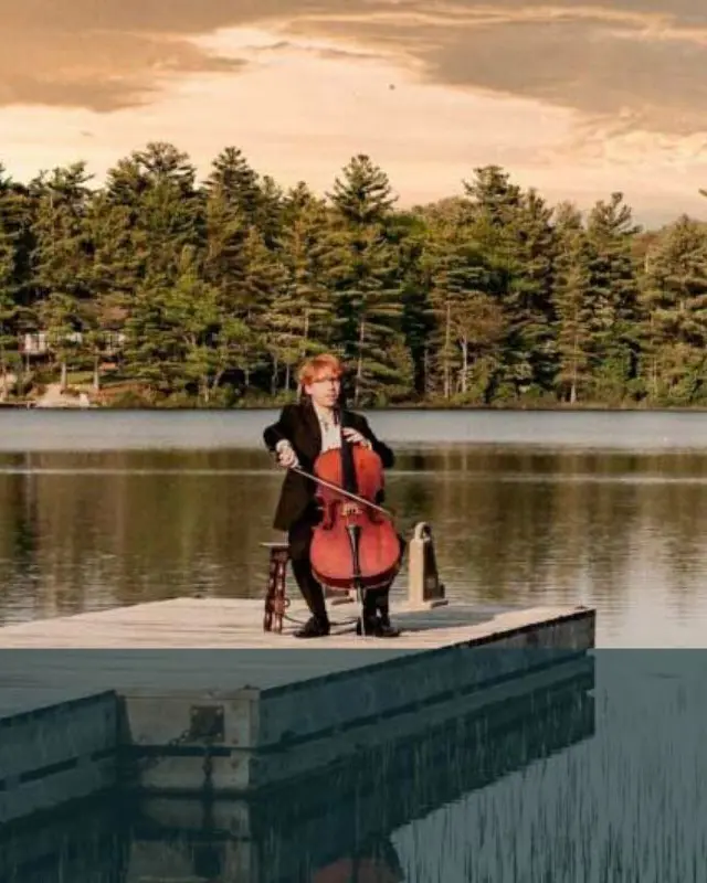 Un homme jouant du violoncelle sur un petit quai flottant entouré de forêt à Parry Sound.