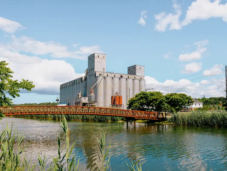 Los silos de grano de Owen Sound y el puente de metal reflejados en el puerto en un soleado día de verano con nubes dispersas.