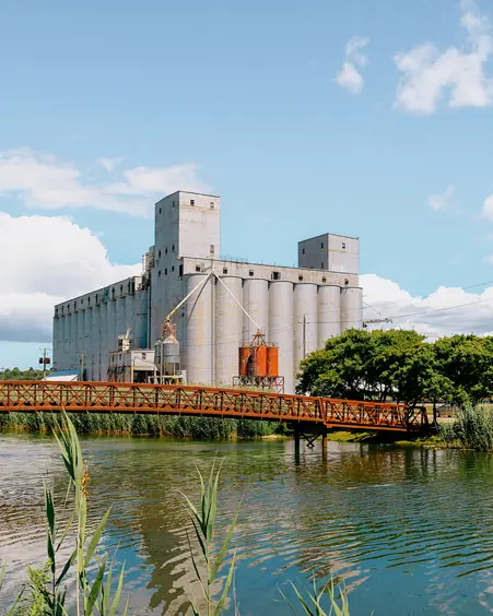 Great Lakes Elevator Co Ltd The Owen Sound grain elevators and metal bridge reflected in the harbour on a sunny summer day with scattered clouds.