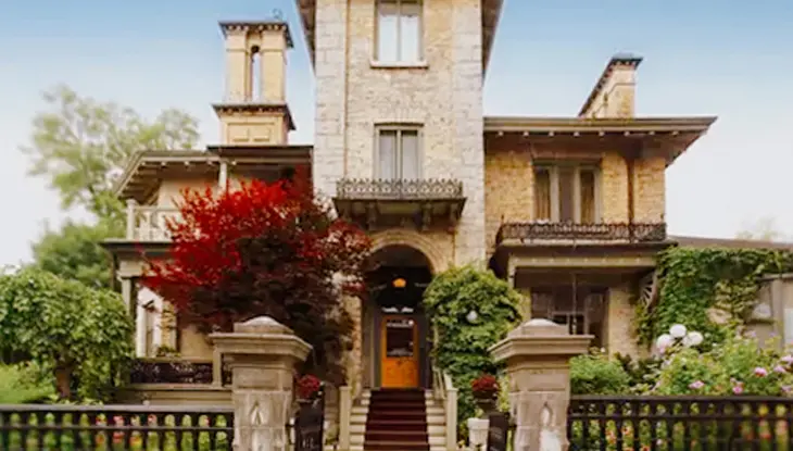 Bâtiment historique en pierre avec tour centrale, entouré de verdure luxuriante et de fleurs de jardin, au Rosemount Inn and Spa, à Kingston.