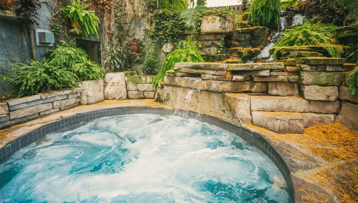 Jacuzzi avec petite chute d’eau, entouré d’un mur en pierre et d’une végétation luxuriante, au Pillar and Post Inn & Spa, à Niagara-on-the-Lake.