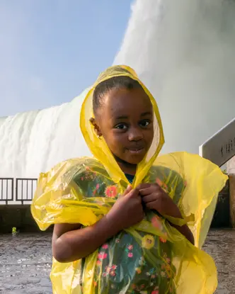 어린 소녀를 포함한 관광객들은 나이아가라 폭포의 안개로부터 자신을 보호하기 위해 폰초를 입습니다.