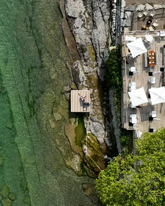 바위 해안과 푸른색 온타리오 호수를 바라보는 레이크사이드 모텔의 햇볕이 잘 드는 데크를 공중에서 본 모습입니다.