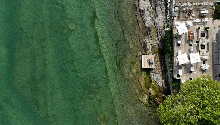 Aerial view of the sunny deck at the Lakeside Motel facing the rocky shore and aqua coloured Lake Ontario.