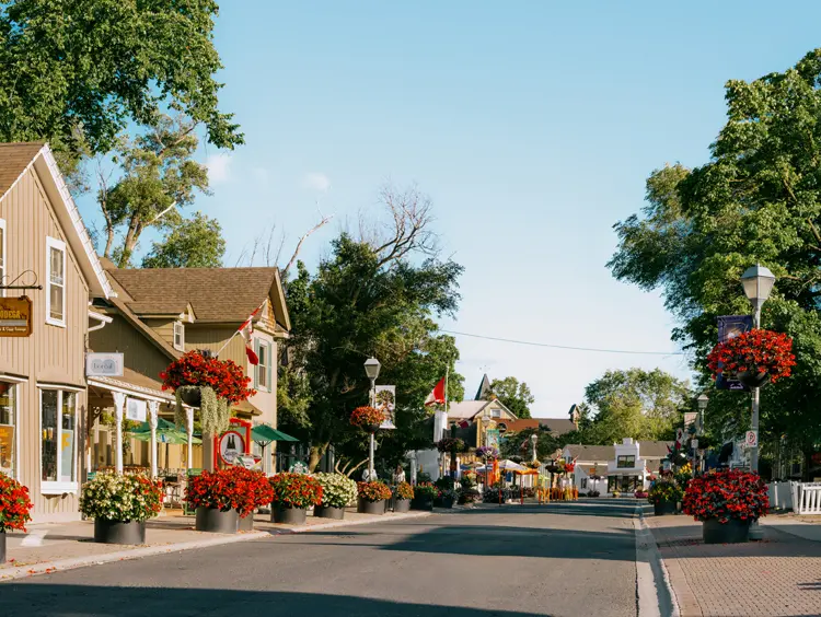 Charmante, blumengeschmückte Hauptstraße in Unionville, Ontario, gesäumt von historischen Gebäuden, Terrassen und Boutiquen an einem sonnigen Tag.
