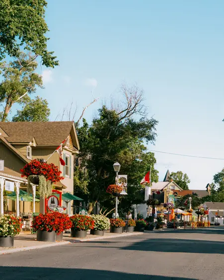 Encantadora calle principal llena de flores en Unionville, Ontario, bordeada de edificios patrimoniales, patios y boutiques en un día soleado.