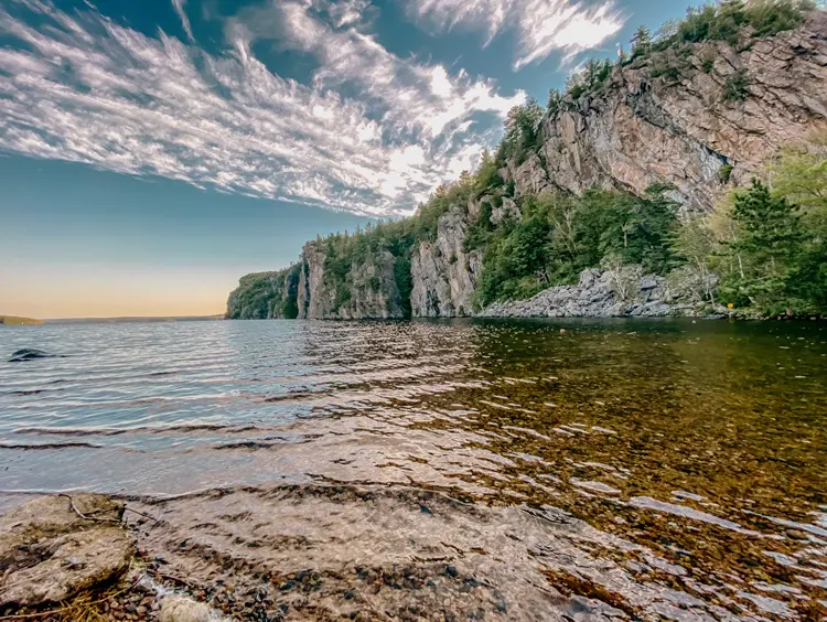 Towering Mazinaw Rock reflecting in the lake on a bright day at Bon Echo Provincial Park.