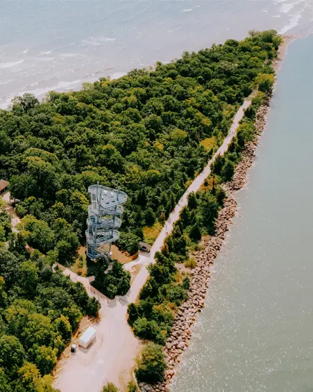 Boardwalk and spiral observation tower winding through lush forest at Point Pelee National Park in Leamington, Ontario, bordered by Lake Erie on both sides.