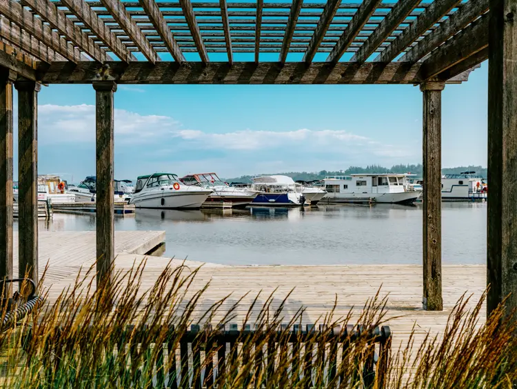 Boote, die am Hafen von Port Perry Marina am Lake Scugog angedockt sind, gesehen von einem Holzüberdach an einem Sommertag.