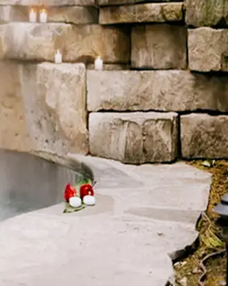 Vapeur s’élevant d’une piscine avec un mur de pierre irrégulier et des bougies disposées sur celui-ci au 100 Fountain Spa, à Niagara-on-the-Lake.