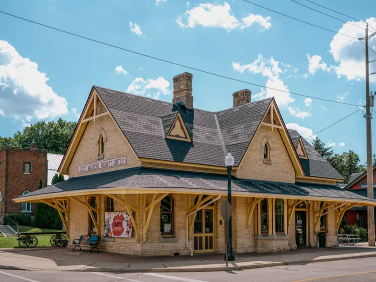 Le Station Arts Centre de Tillsonburg, situé dans une gare historique restaurée, photographié par une journée d’été ensoleillée avec des nuages épars.