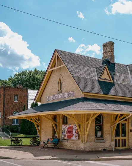 Das Station Arts Centre in Tillsonburg, untergebracht in einem restaurierten historischen Bahnhofsgebäude, abgebildet an einem sonnigen Sommertag mit verstreuten Wolken.