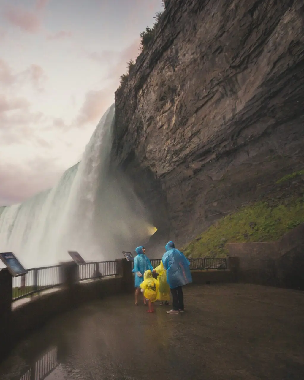 Menschen in blauen und gelben Regenmänteln schützen sich vor dem Nebel der Niagarafälle.