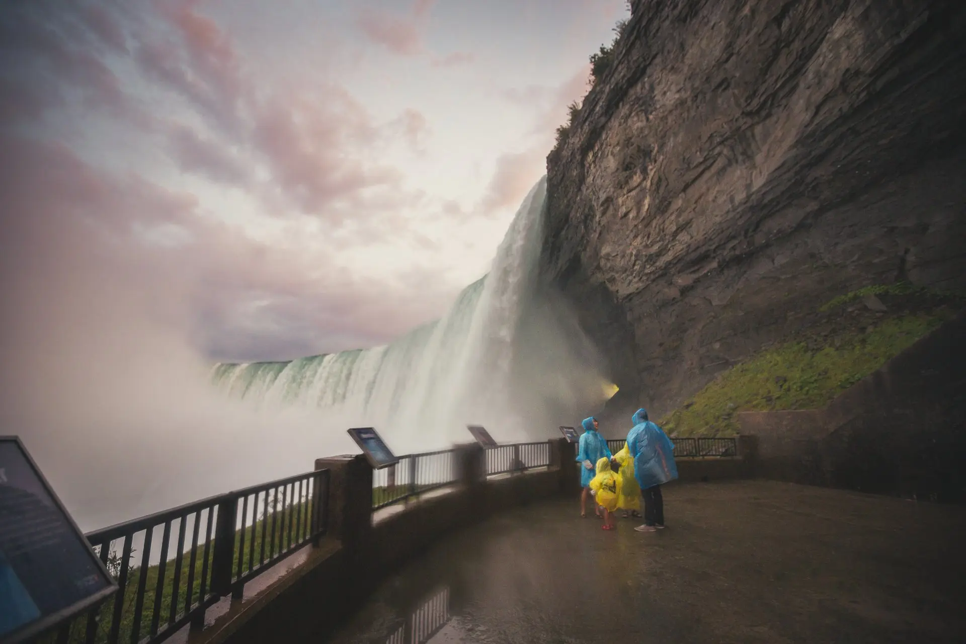 Personas con impermeables azules y amarillos se protegen de la niebla de las cataratas del Niágara.