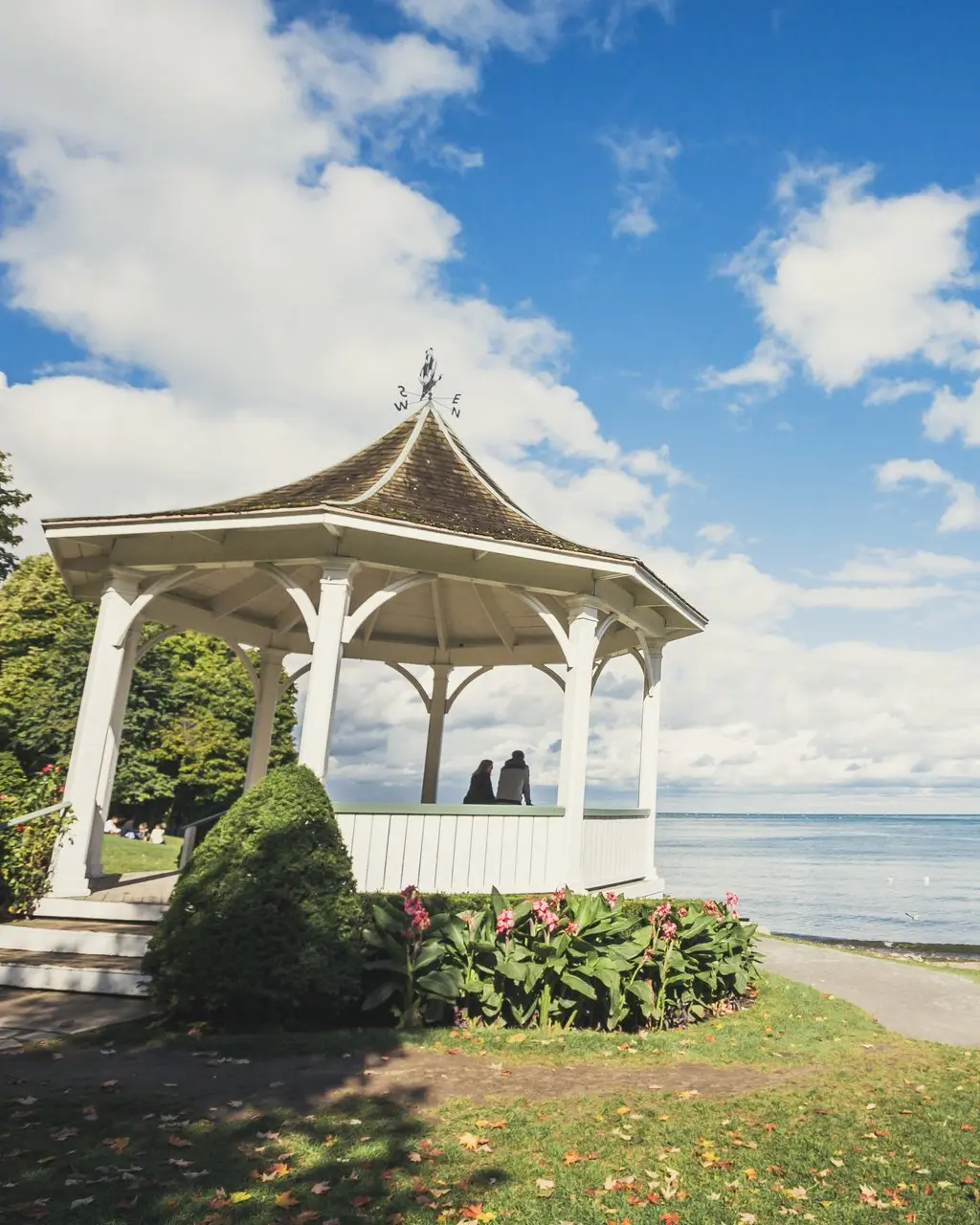 Two people in a white gazebo in Queen's Royal Park in Niagara-on-the-Lake looking out to Niagara River.