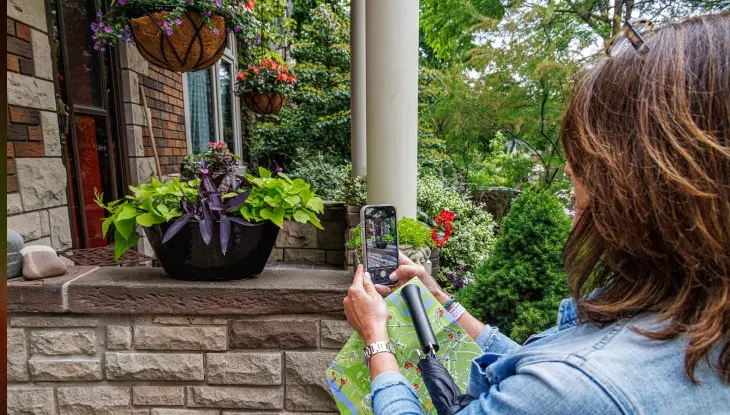 A woman taking a photo of a garden on a garden tour.