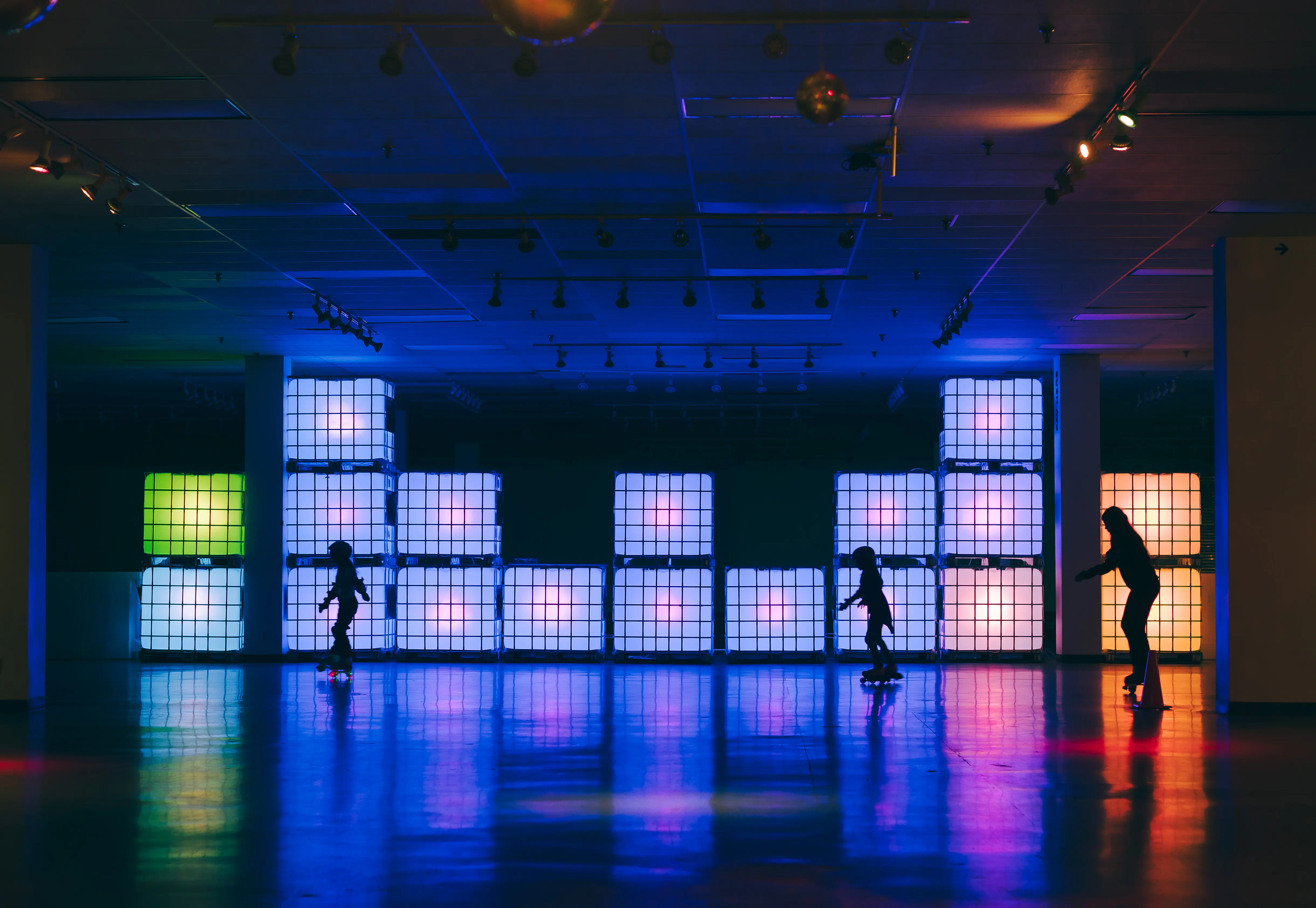 Tres niños patinando frente a bloques coloridos que brillan.