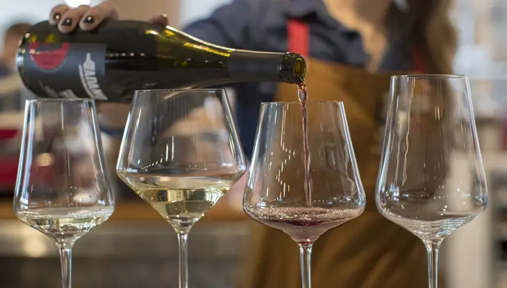 Eine Person gießt Rotwein in ein Glas für eine Weinprobe im Adamo Estate Winery.
