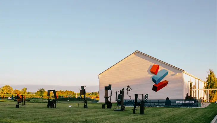  Eine weiße Scheune auf einem flachen, grünen Weingut unter einem klaren blauen Himmel.