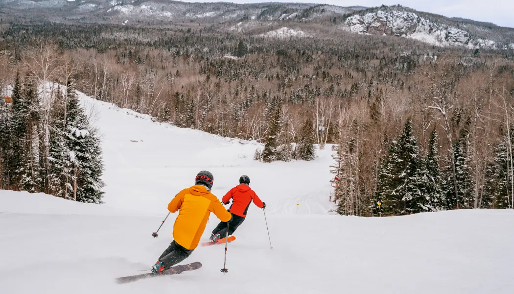 Deux skieurs alpins dévalant une pente enneigée au centre de villégiature Searchmont, près de Sault Ste. Marie.