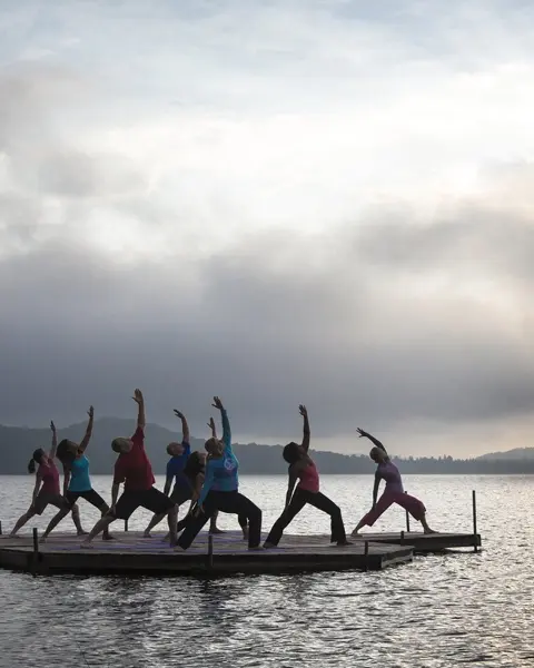 A group of people doing yoga on a wooden dock facing the lake in Northern Ontario.