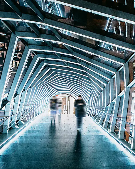 Passerelle futuriste illuminée avec des parois en verre et un design géométrique à Toronto, scintillant d’une lumière blanche.