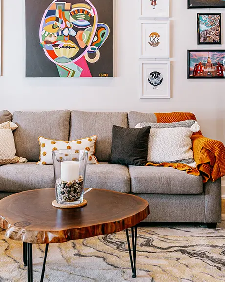 Moderna sala de estar con sofá seccional, mesa de café y obras de arte coloridas exhibidas en las paredes.