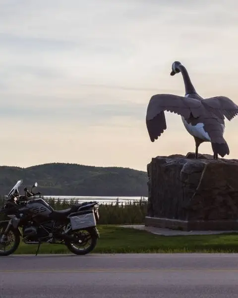 온타리오주 와와에 있는 슈피리어 호수가 내려다보이는 유명한 거위 조각상 양쪽에 오토바이 두 대가 주차되어 있습니다.
