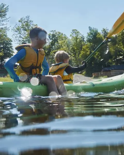 Deux jeunes garçons faisant du kayak et jouant dans un lac par une belle journée d’été.