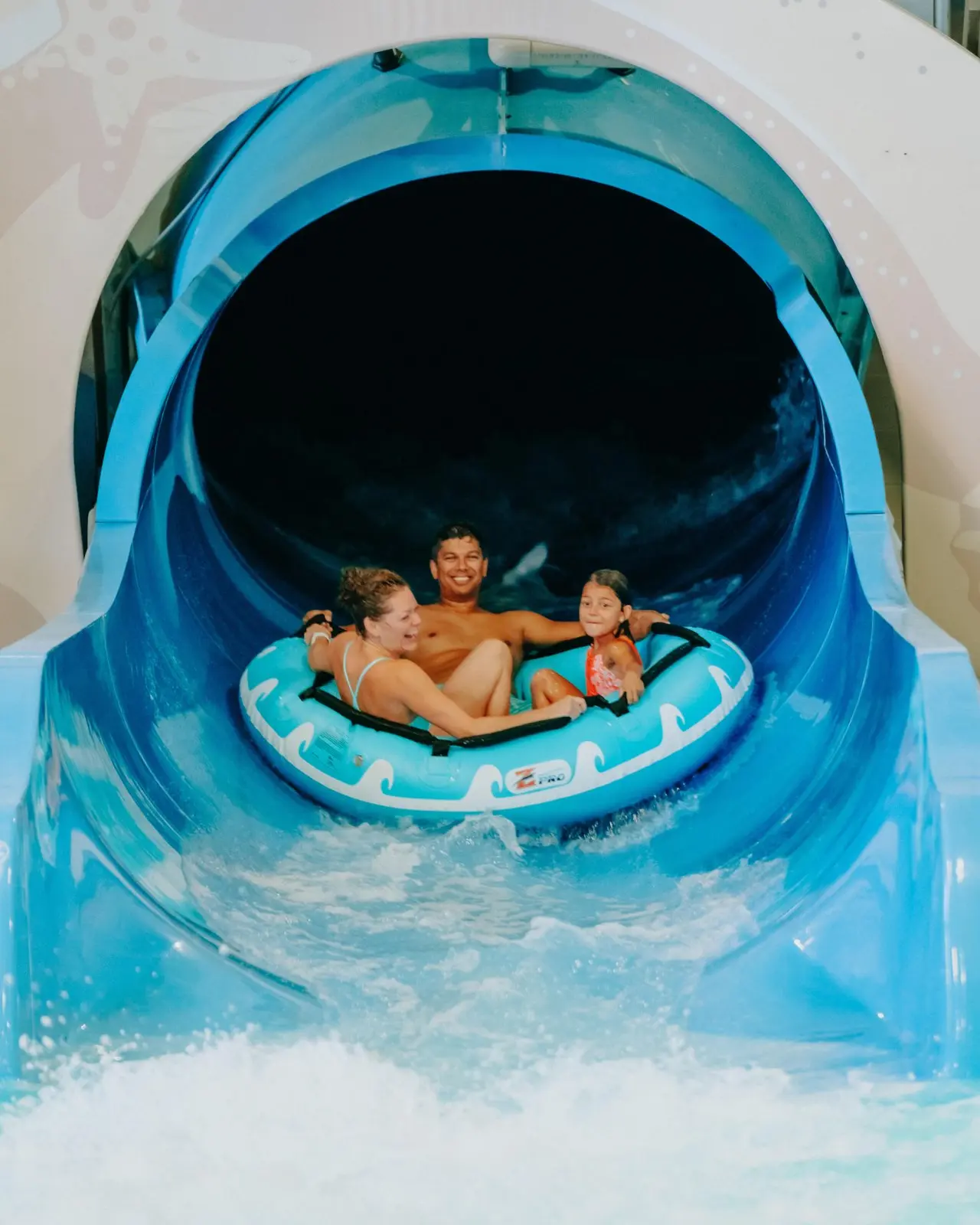 Une famille profitant d'un toboggan aquatique sur une bouée au parc aquatique Adventure Bay Family Water Park.