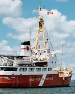 A large ship used for breaking ice, creating trading opportunities pictured in the open sea under the fluffy white clouds.