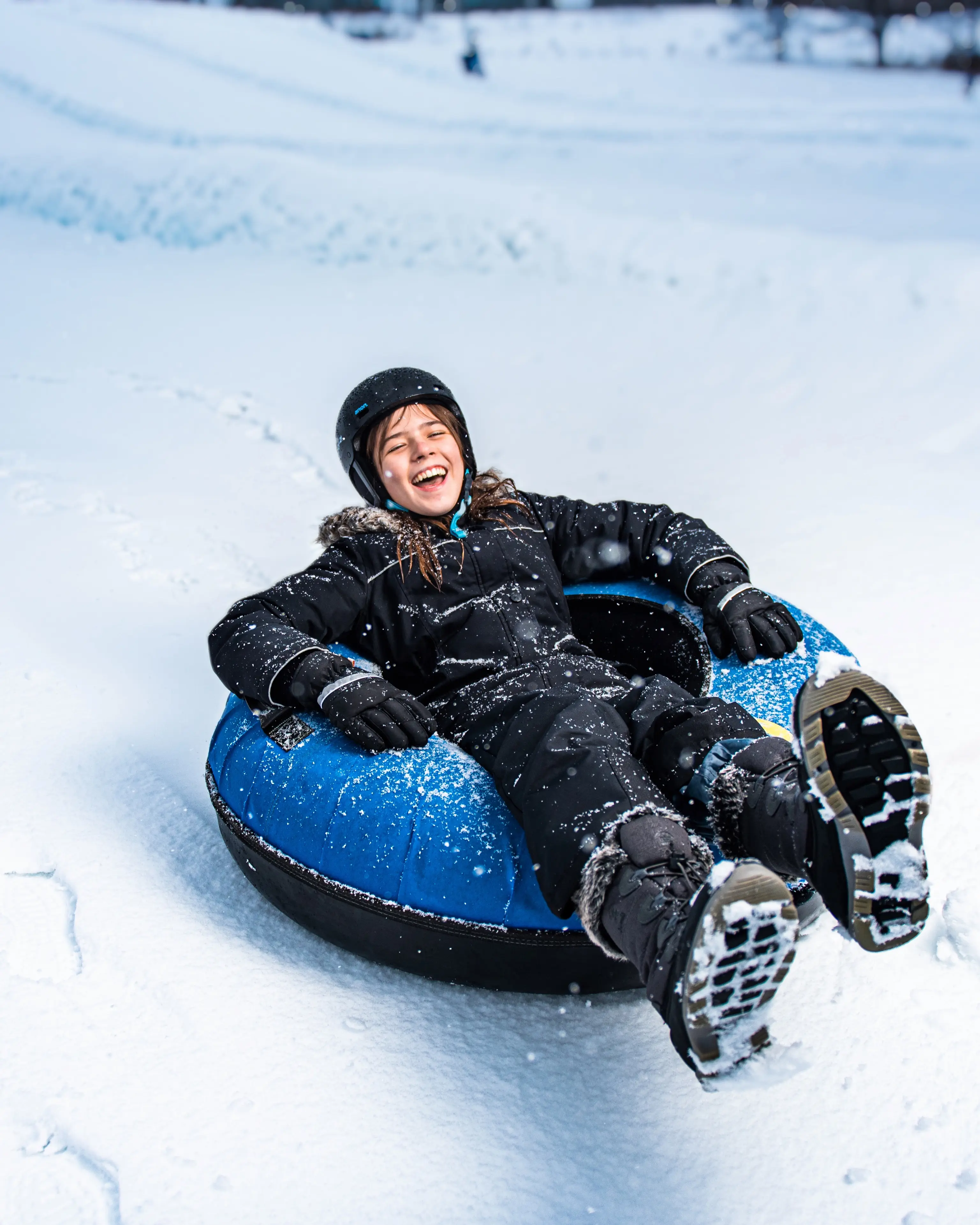Un enfant descend la côte en bouée sur neige à Boler Mountain.