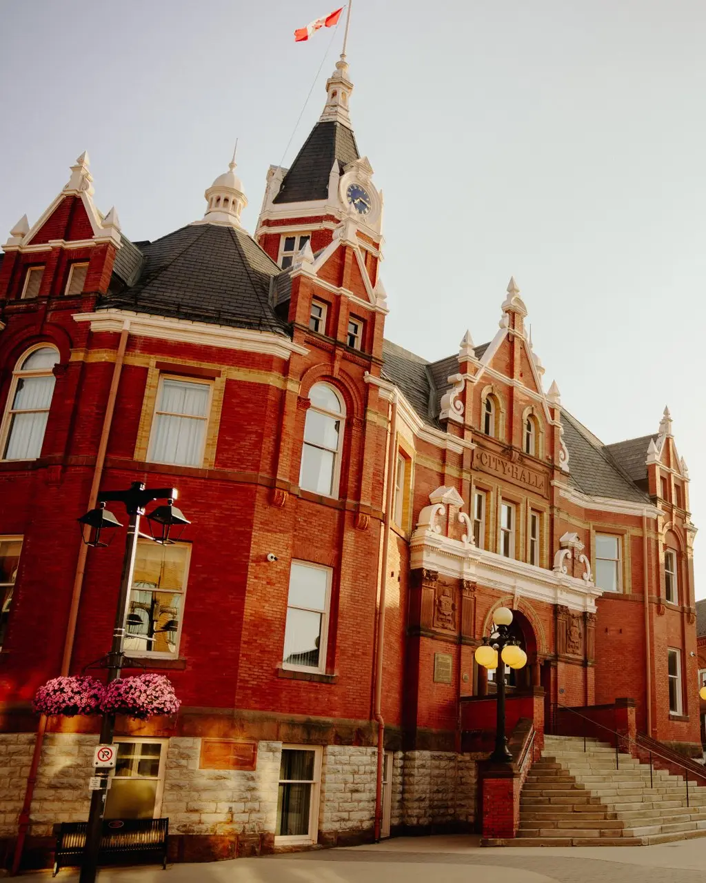 Stratford's red brick City Hall with a clock tower and Canadian flag, overlooking the downtown street below.