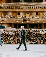 On stage view of ballet dancers perofrming in front of a large audience.
