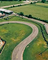 Circuito Wasaga 500 con campos abiertos, arbustos y un estacionamiento. 