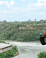 Deux personnes faisant de la tyrolienne au-dessus d’un lac.