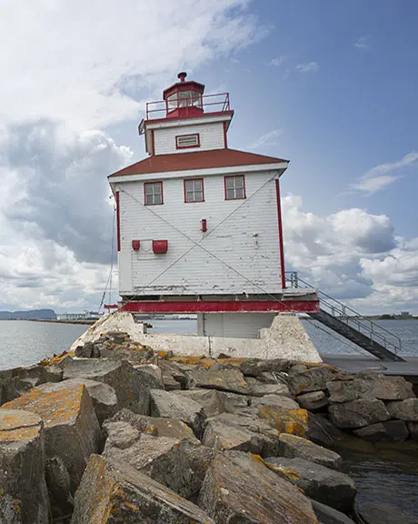 Der weiße Leuchtturm von Thunder Bay mit rotem Rand und Blick aufs Wasser.