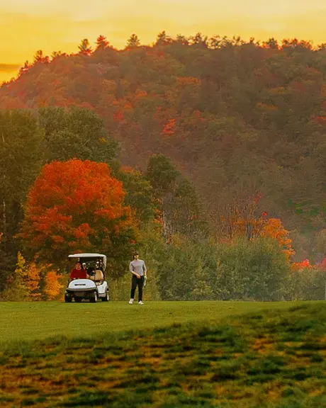 Golfers enjoy fall season golf on lush fairways with gorgeous autumn colour in the background.