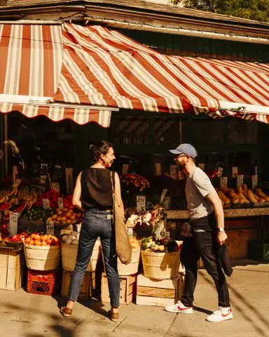 Zwei Personen unterhalten sich vor einem Obst- und Gemüsestand