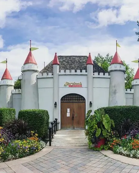 Ein weißes Schloss und große Holztüren am Eingang zu einem Themenpark.