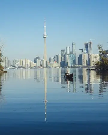 A person canoes in the water near the Toronto Islands.